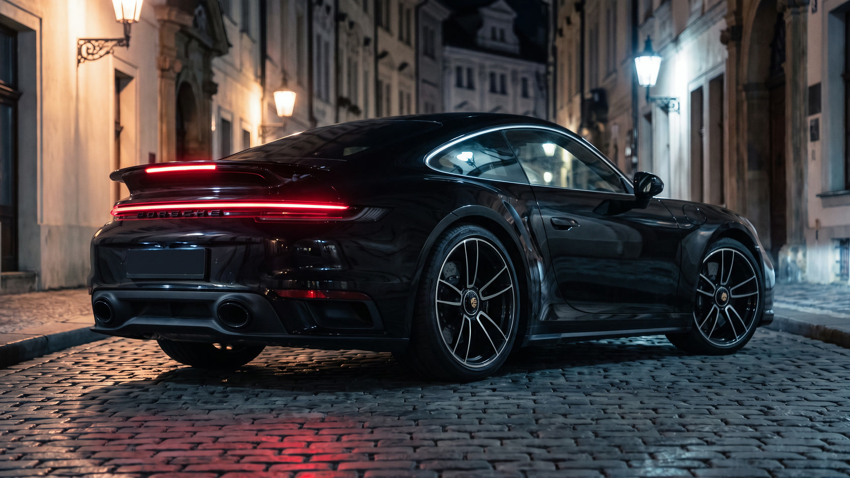 Černé Porsche 911 Turbo S zezadu na noční pražské ulici